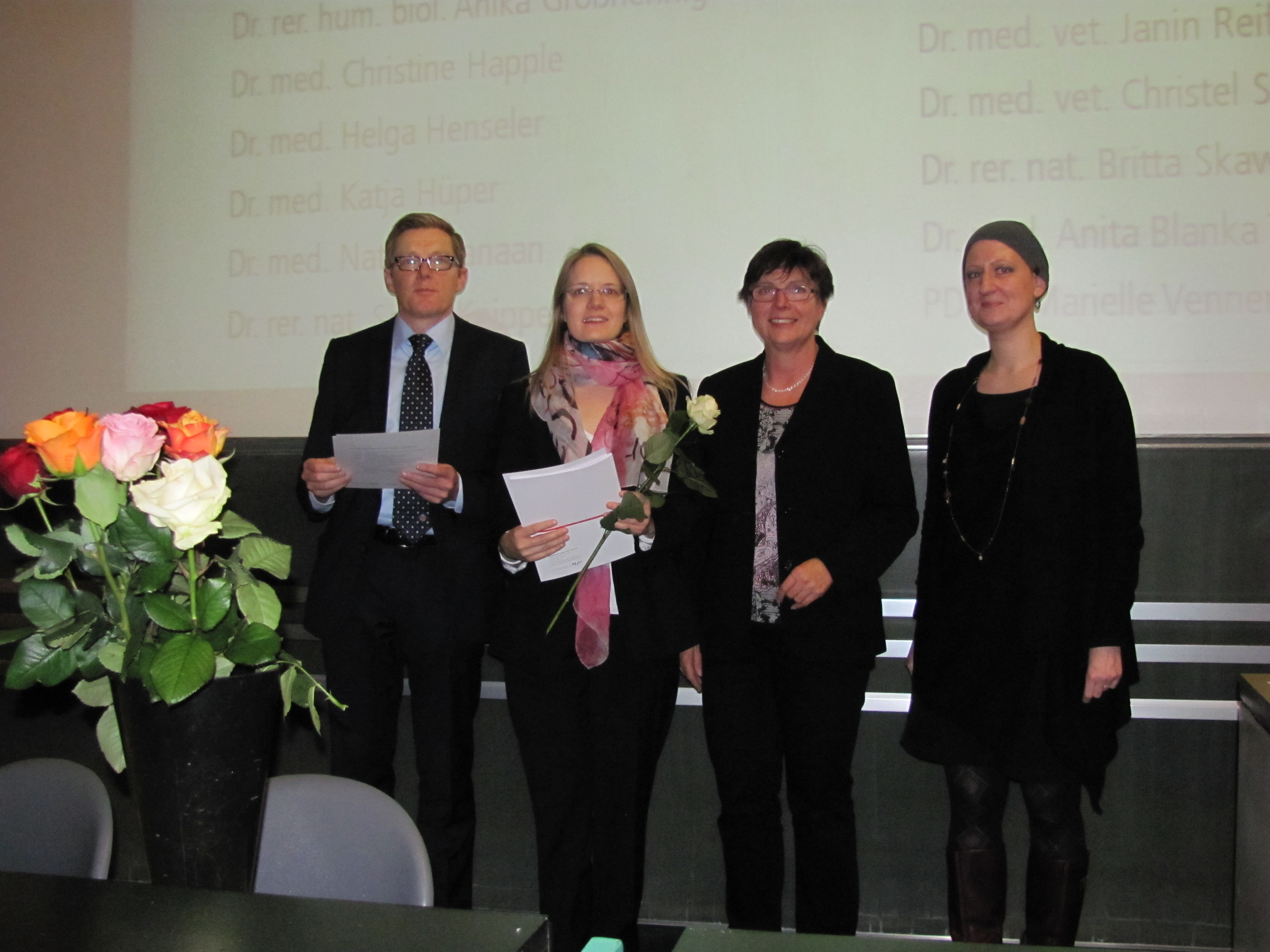 Vier Personen stehen vor einer Leinwand im Hörsaal, darunter Prof. Dr. Christopher Baum, später Präsident der MHH (2013 - 2018), die damalige Programmleitung Dr. Bärbel Miemietz und die damalige Programmkoordination Britta Möller. 
