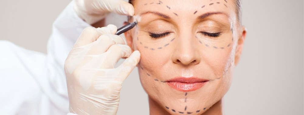 Chirurg zeichnet im Gesicht einer Patientin für eine OP vor.