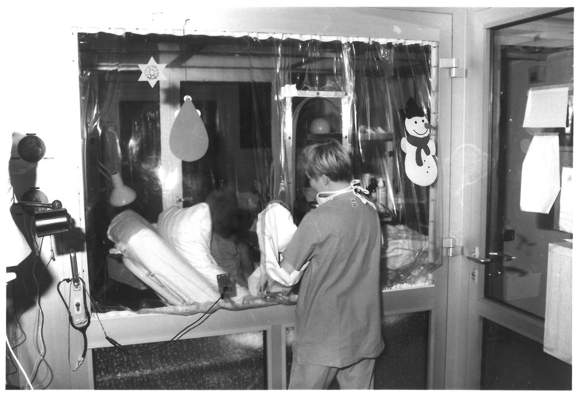 Historical photograph: A nurse stands at the bedside in the bone marrow transplantation ward.