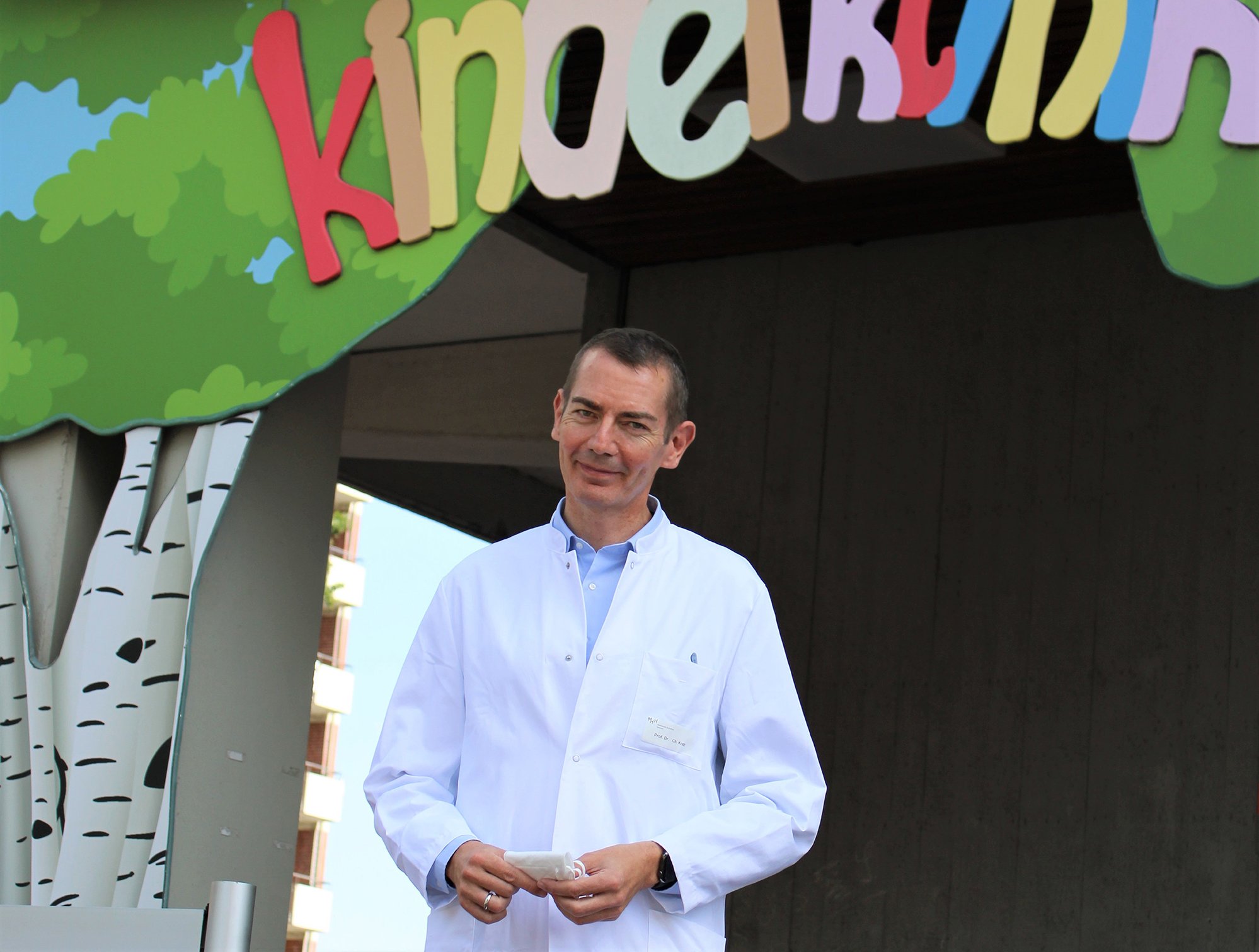 Professor Dr. Christian Kratz steht vor dem Eingang der Kinderklinik.