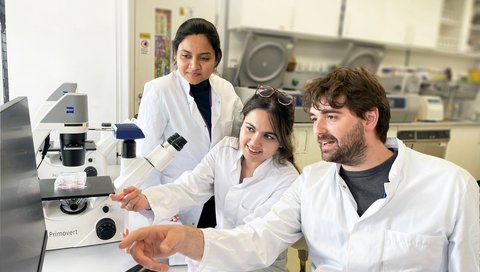 Dr Florian Perner sits in a laboratory with two employees.