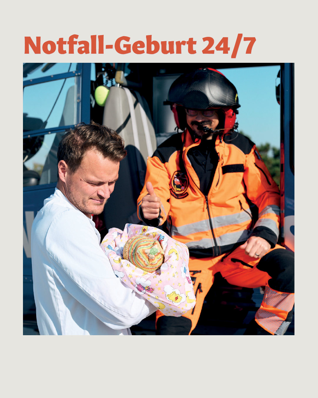 Arzt hält Baby im Arm und steht neben Helikopter Christoph 4 der MHH mit HEMS