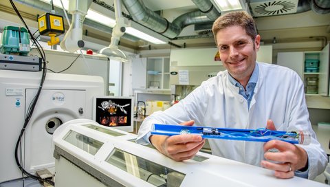 Professor Dr. James Thackeray steht hinter einem Einzelphotonen-Emissionscomputertomographen 