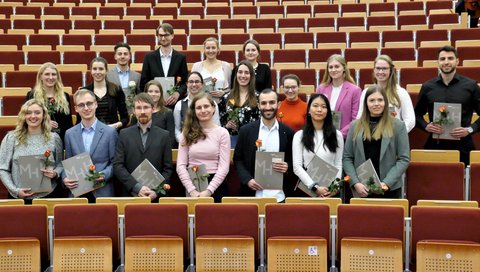 Mehrere Absolventen des Masterstudiengangs Biochemie stehen nebeneinander in einem Hörsaal der MHH und halten ihre Urkunde in den Händen. 