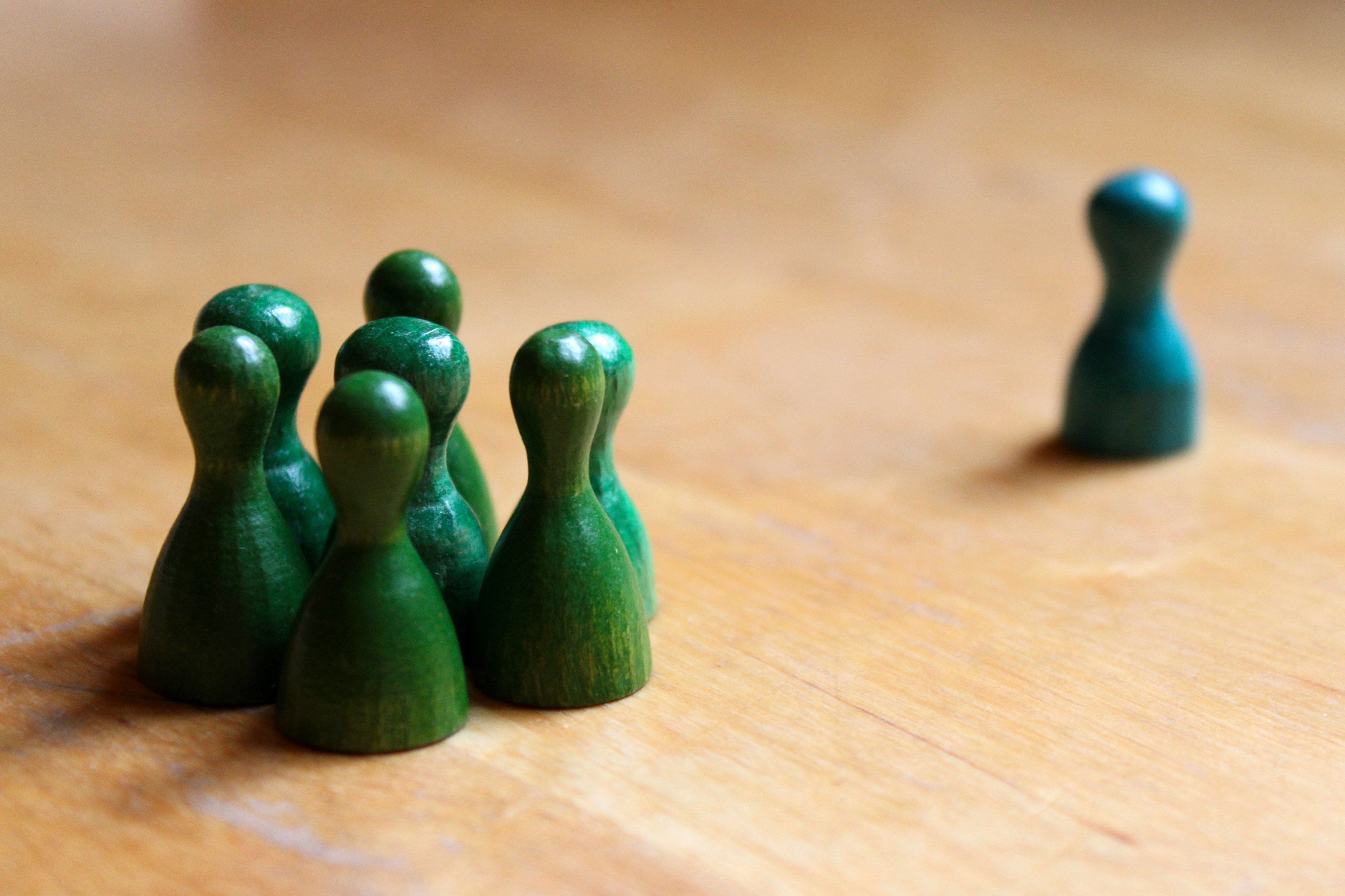 grüne Spielfiguren zusammenstehend als Gruppe, eine Spielfigur einzeln isoliert