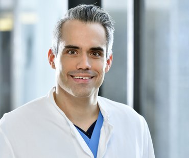 Porträtbild von Markus Busch, der einen weißen Arztkittel trägt