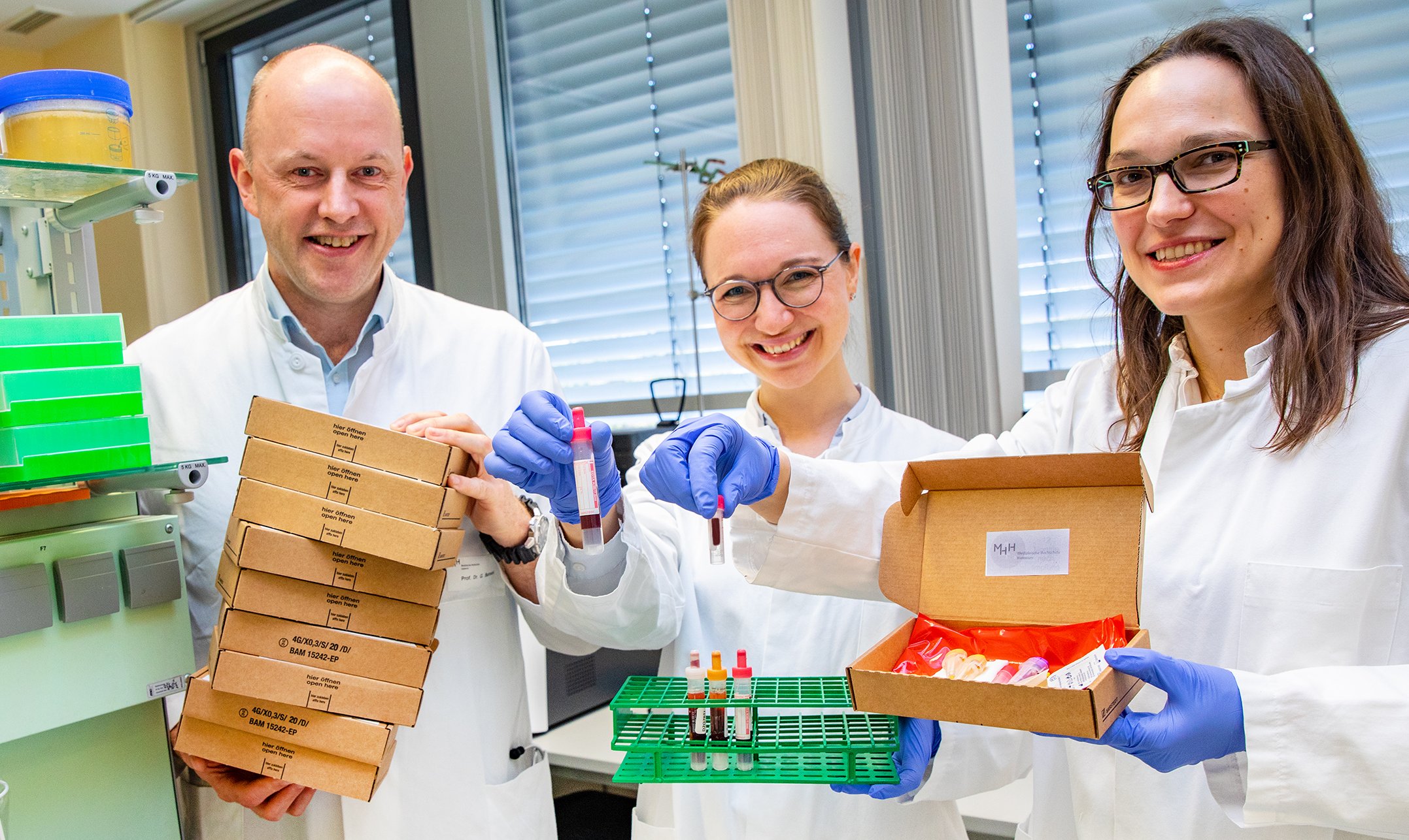 Copyright: Karin Kaiser / MHH Professor Dr. Georg Behrens, die Wissenschaftliche Mitarbeiterin Anne Cossmann (Mitte) und Professorin Dr. Alexandra Dopfer-Jablonka präsentieren Versandboxen und Blutentnahmeröhrchen.