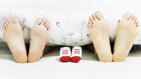 Zwei paare Füße am Deckenende und in der mitte Babyschuhe