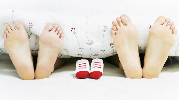 Zwei paare Füße am Deckenende und in der mitte Babyschuhe