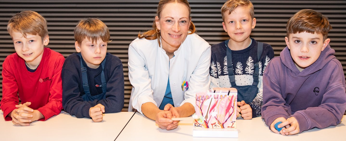 Dr. Eva Moennig umringt von vier jungen Studierenden im Hörsaal F.