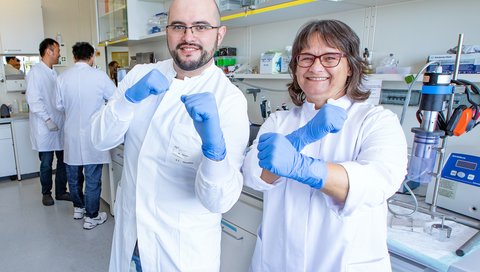 Auf dem Foto sind Professorin Sodeik und Dr. Manutea Serrero in einem Labor des Instituts für Virologie zu sehen. Sie tun so, als würden sie boxen – um darzustellen, dass das Protein MxB die Kapside der Herpesviren attackiert.
