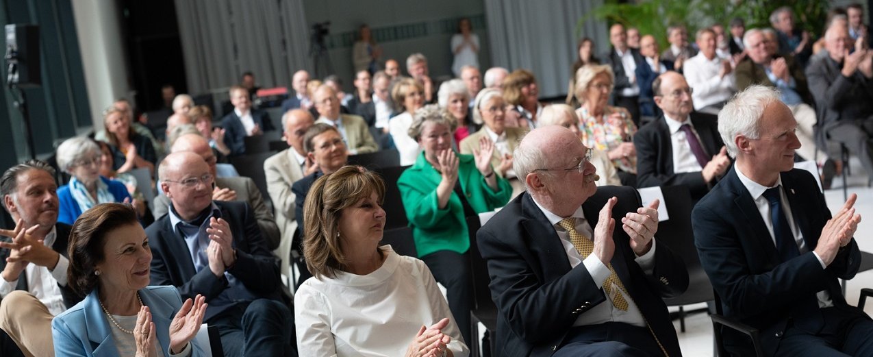 Die Gäste der Jubiläumsveranstaltung der Gesellschaft der Freunde der MHH sitzen auf Stühlen und klatschen Applaus. 