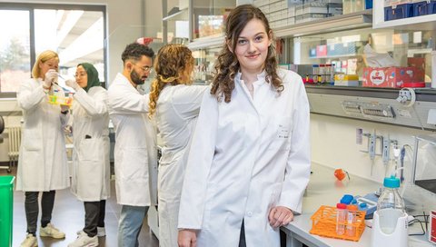 The young doctor Dr Laura Hinze stands in her laboratory with her research group.