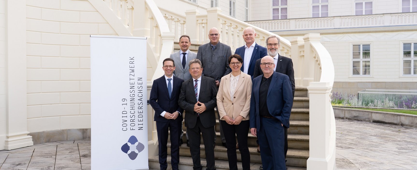 Mehrere Personen stehen für ein Gruppenbild auf einer Treppe vor dem Tagungszentrum Schloss Herrenhausen