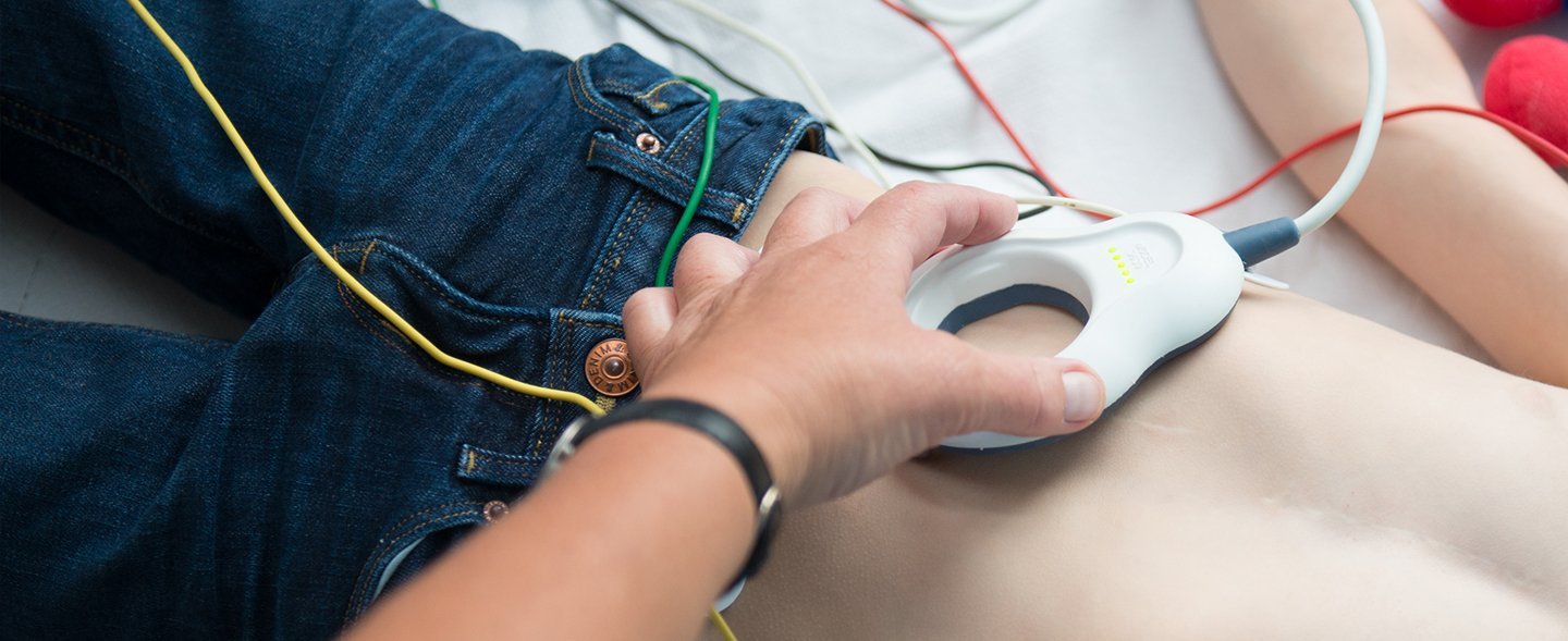 Verkabelter Oberkörper eines Jungen im Bett. Der Junge wird von einer Ärztin untersucht.
