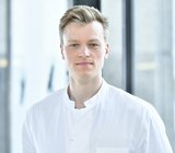 Copyright: Tom Figiel Porträtbild von Tammo Tergast, der einen weißen Arztkittel trägt.