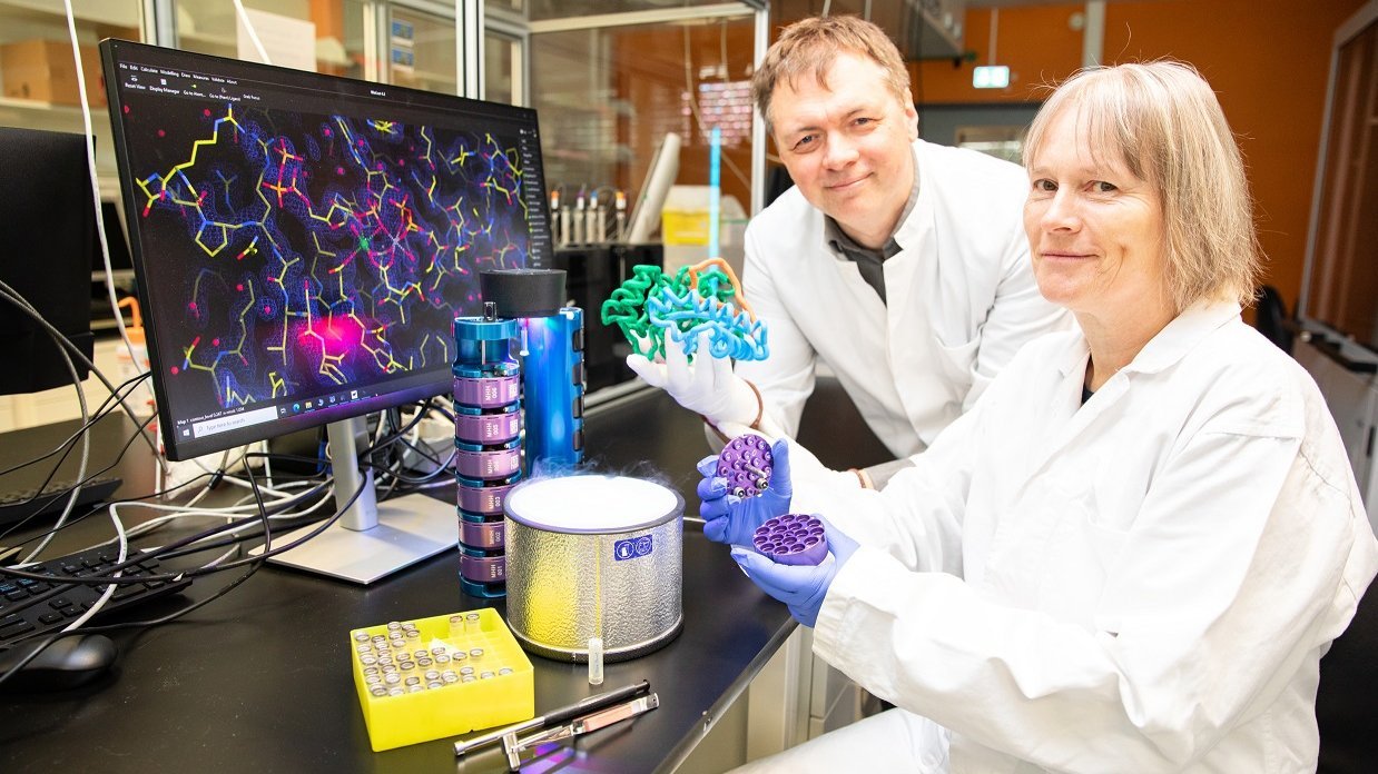 Prof. Dr. Roman Fedorov (links) und Petra Baruch sitzen in einem Labor an einem Tisch und halten Protein-Modell in den Händen. 