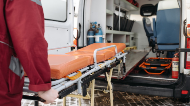 A person is pushing a stretcher into an ambulance.