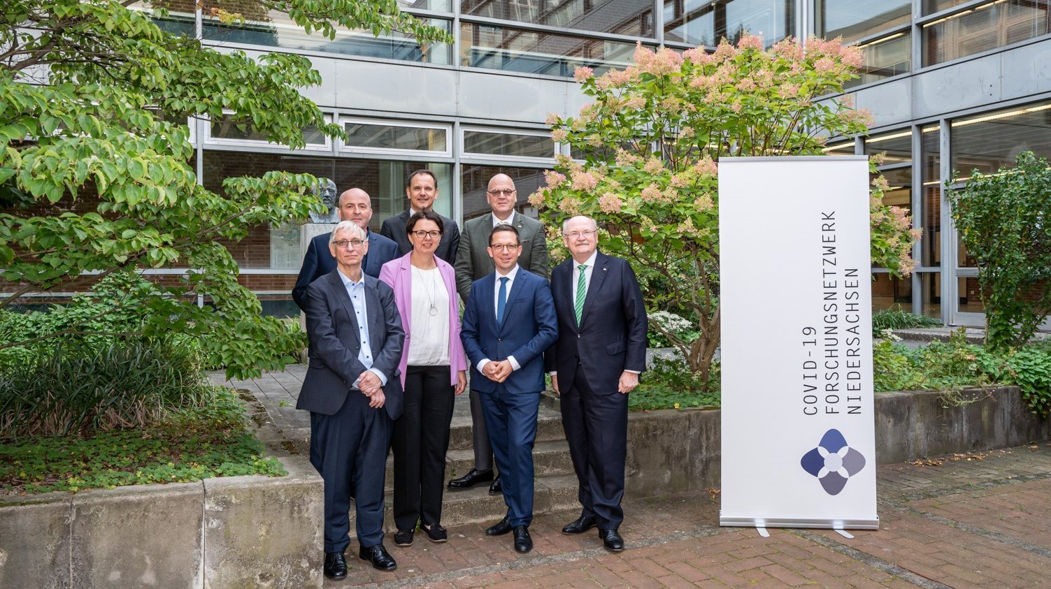 Gruppenbild draußen in einem Innenhof der MHH mit Prof. Dr. Tobias Welte (MHH), Prof. Dr. Maren von Köckritz-Blickwede (TiHo), Wissenschaftsminister Falko Mohrs, Prof. Dr. Michael Manns (MHH), hintere Reihe: Prof. Dr. Berthold Vogel (UMG), Prof. Dr. Jürgen Wienands (UMG), Prof. Dr. Wolfgang Brück (UMG).