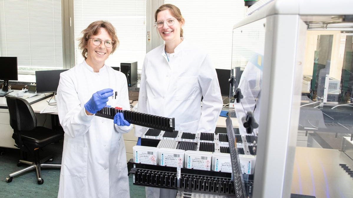  Dr. Katja Dinkelborg, PHD (rechts) und Birgit Bremer Medizinische Technologin für Laboratoriumsanalytik stehen in einem Labor und halten Blutproben in den Händen. 