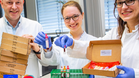 Professor Dr. Georg Behrens, die Doktorandin Anne Cossmann (Mitte) und Professorin Dr. Alexandra Dopfer-Jablonka präsentieren Versandboxen und Blutentnahmeröhrchen.