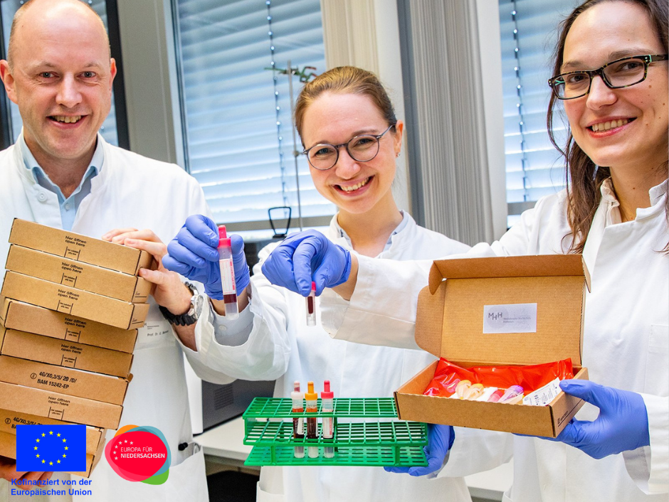 [Translate to Englisch:] Professor Dr. Georg Behrens, die Doktorandin Anne Cossmann (Mitte) und Professorin Dr. Alexandra Dopfer-Jablonka präsentieren Versandboxen und Blutentnahmeröhrchen.