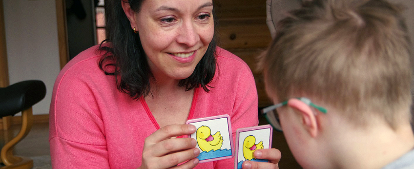 Charlotte Bonecke sitzt vor ihrem Sohn Carlo und hält kleine Spieltafeln in den Händen. 