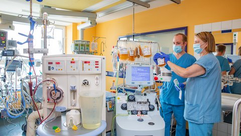 Ein Arzt und eine Fachkrankenschwester stehen an einem Plasmaaustausch-Gerät in einem Patientenzimmer.