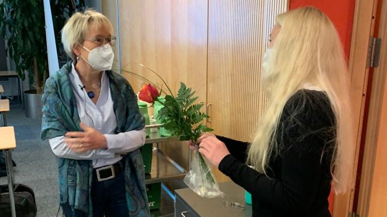 Copyright: Stephanie Stiel Frau Dr. Stumme (links im Bild) und Professorin Stephanie Stiel (rechts) im Gespräch. Beide Frauen tragen eine Atemschutzmaske.Frau professorin Stiel hält eine Rose in den Händen.