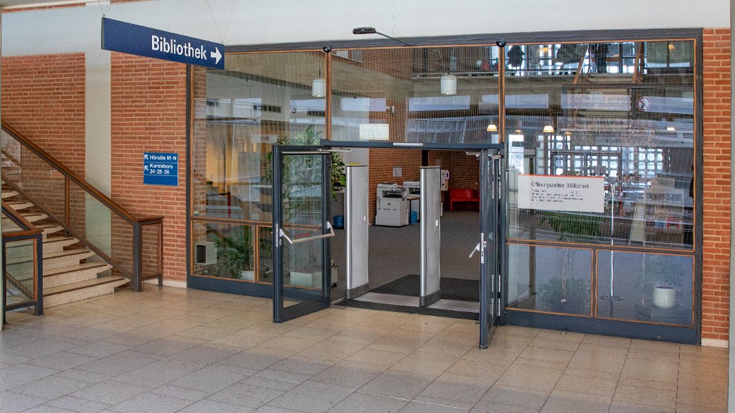 Der Eingangsbereich der Bibliothek mit geöffneten Türen und Blick ins Foyer durch die großen Glasscheiben