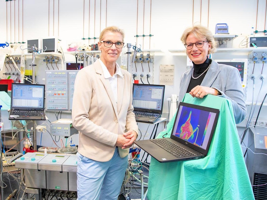 Zwei Frauen stehen im Labor und betrachten ein Wärmebild auf einem Laptop-Bildschirm.