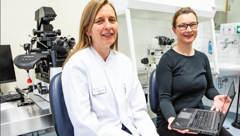 Professorin Dr. Frauke von Versen-Höynck und Dr. Yvonne Ziert sitzen vor einem Spezialmikroskop für die Durchführung einer künstlichen Befruchtung in einem Labor der Frauenklinik. 