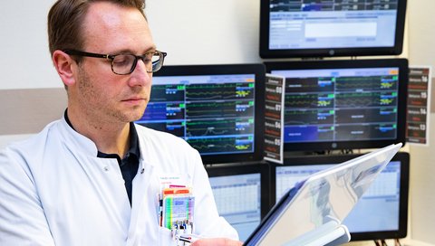 PD Dr. Gerrit Große hält eine Akte in der Hand und schaut sich klinische Daten von Schlaganfall-Patientinnen und -Patienten auf der Stroke Unit an.