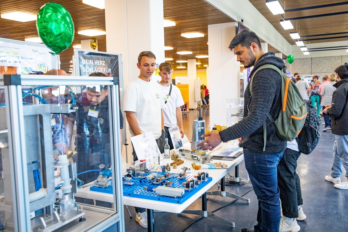 Ein junger Mann steht an einem Stand mit elektronischen Schaltsystemen. 