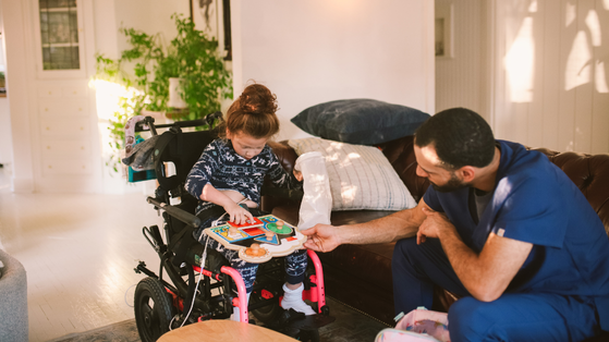 A man is playing with a girl in a wheelchair.