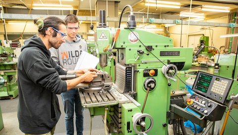 Nico Hausmann und Nathan Duhm stehen an der Fräsmaschine in den Forschungswerkstätten