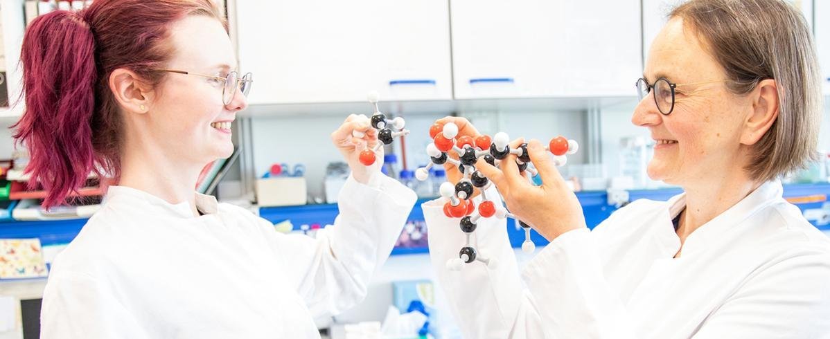 Zwei Wissenschaftlerinnen stehen in einem Labor und halten Molekülmodelle eines Zuckerbausteins in den Händen.