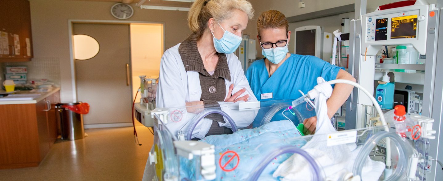 Professorin Viemann und PD Dr. Sabine Pirr stehen am Bett eines Frühgeborenen, das sich auf der Station für Neu- und Frühgeborene der Medizinischen Hochschule Hannover befindet, und schauen dort hinein.