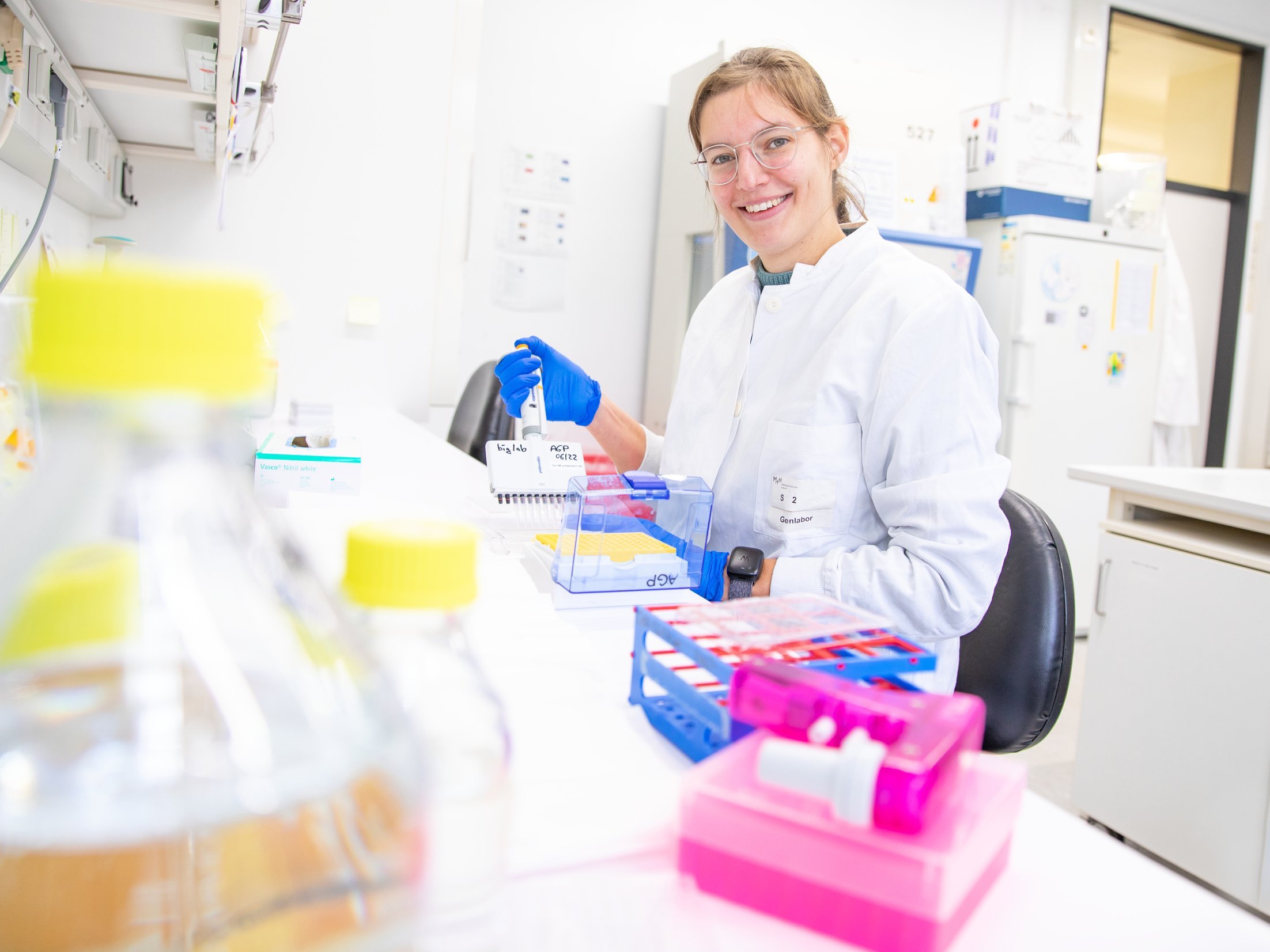 Eine Ärztin im weißen Kittel steht in einem Forschungslabor. 