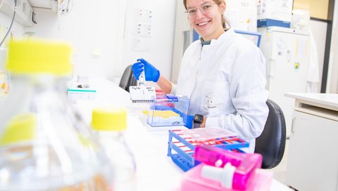 A physician in a white coat is standing in a research laboratory. 