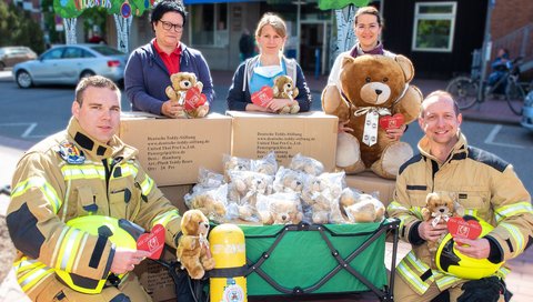 Ein Gruppenbild vor der Kinderklinik mit den Feuerwehrmännern und den Teddybären