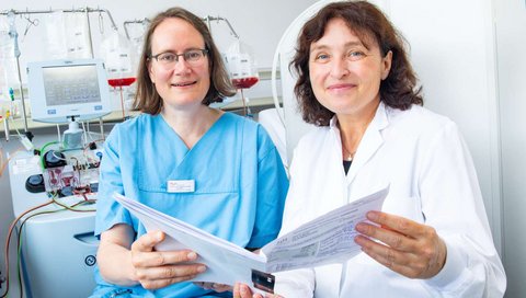 Professorin Dr. Maecker-Kolhoff (links) und Professorin Dr. Britta Eiz-Vesper sitzen im Institut für Transfusionsmedizin und halten eine Patientenakte in den Händen. Copyright: Karin Kaiser / MHH  