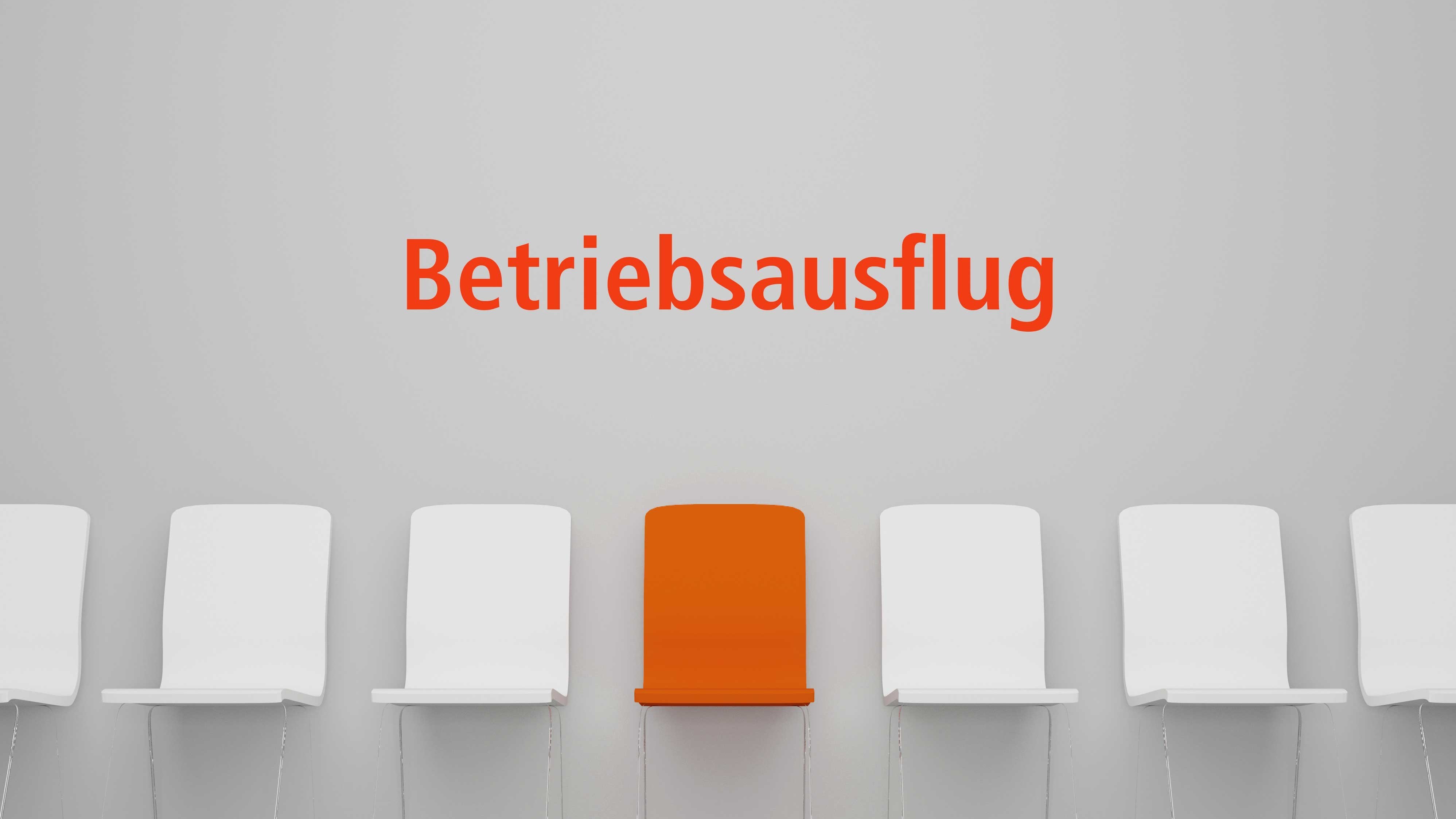 Schriftzug Betriebsausflug über einer Reihe von weißen Stühlen, wobei einer rot ist
