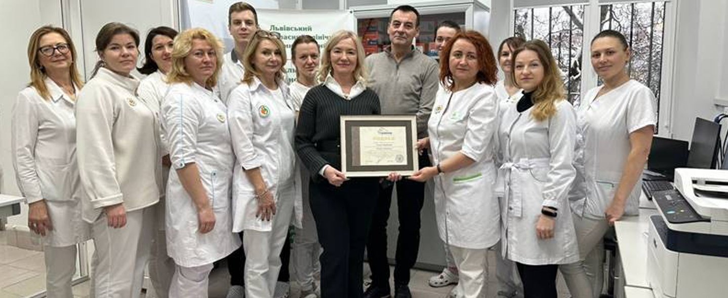 Mehrere Personen stehen für ein Gruppenbild zusammen, zwei in der Mitte halten eine eingerahmte Urkunde in den Händen. 