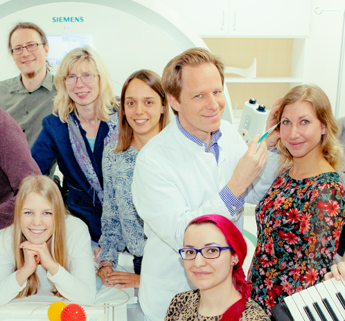 Colleagues of the research group who are standing in front of an MRI machine.