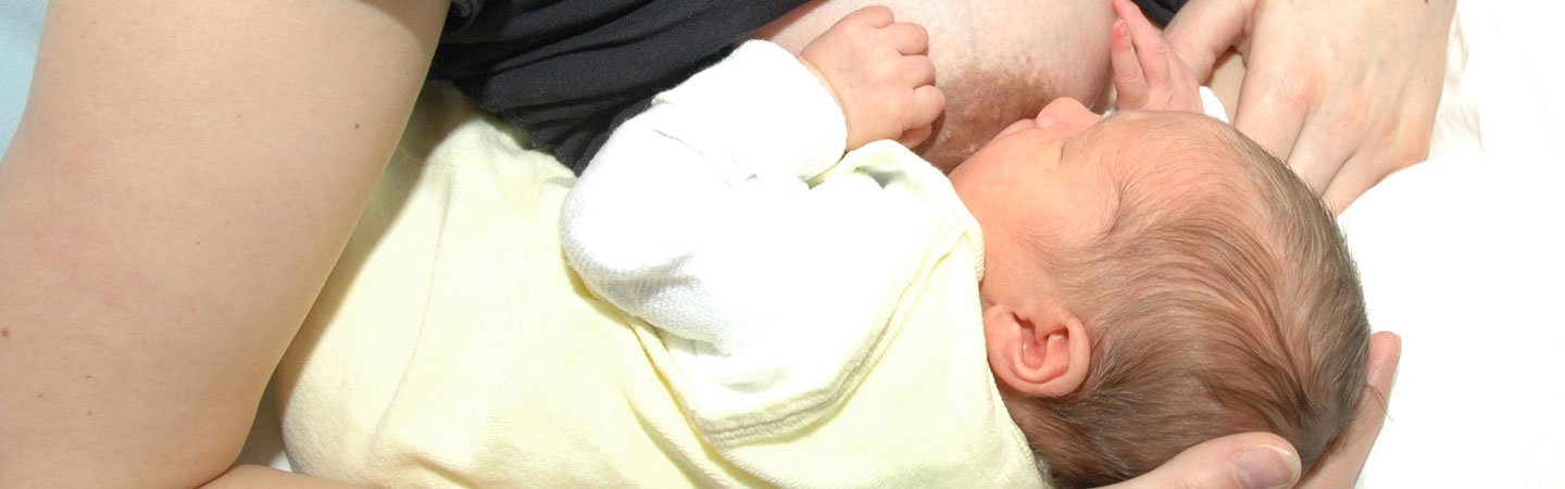 Mutter hält Baby zum Stillen auf dem Arm