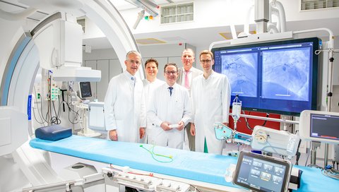 Five men stand at a cardiac catheterization unit.