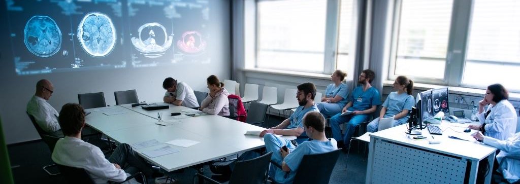 Copyright: medJUNGE Mehrere Ärzte die sich zu Bildern im Molekularen Tumorboard besprechen.