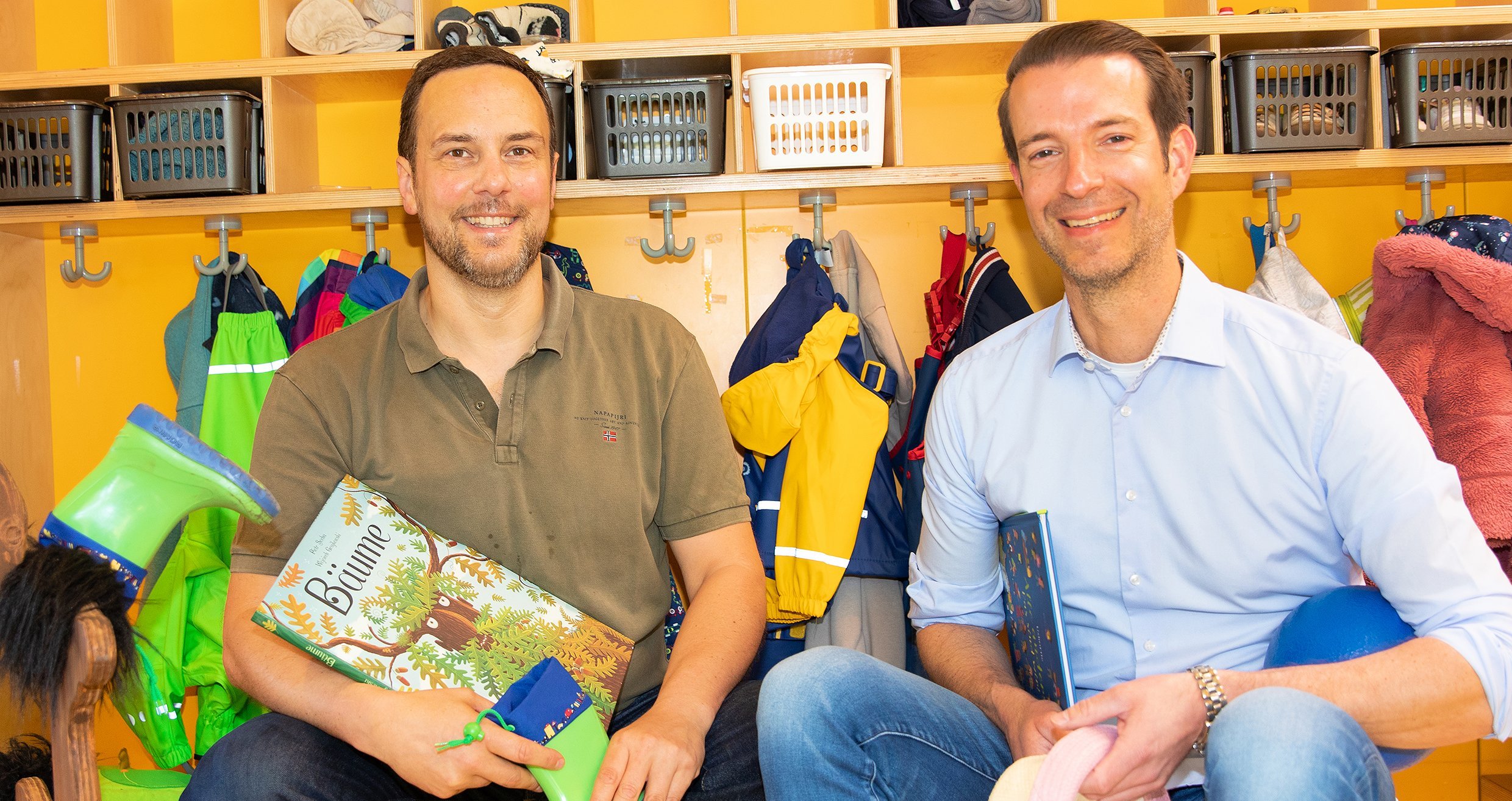 CPD Dr. C. Sturm und Prof. Dr. Dingemann sitzen vor der Garderobe in der Kita