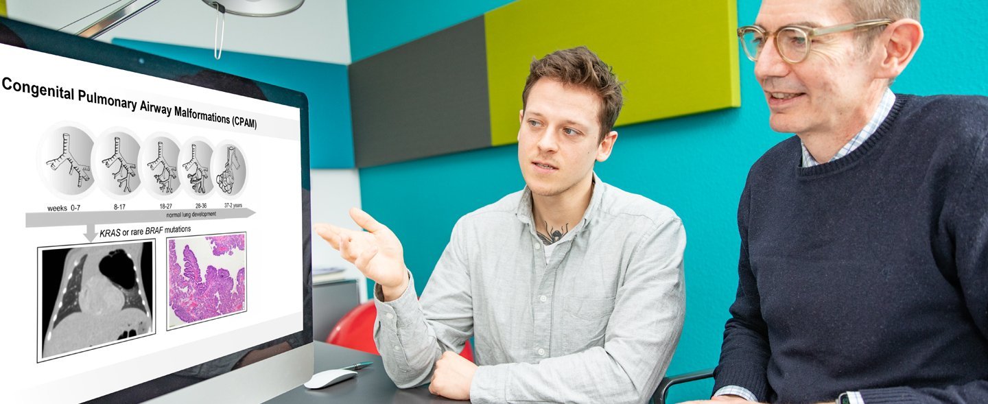 Zwei Männer sitzen am Schreibtisch und schauen sich am Bildschirm Aufnahmen der Lunge an.